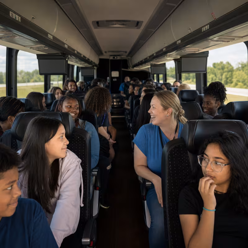 Group boarding a white charter bus for School Transportation transportation in Orange